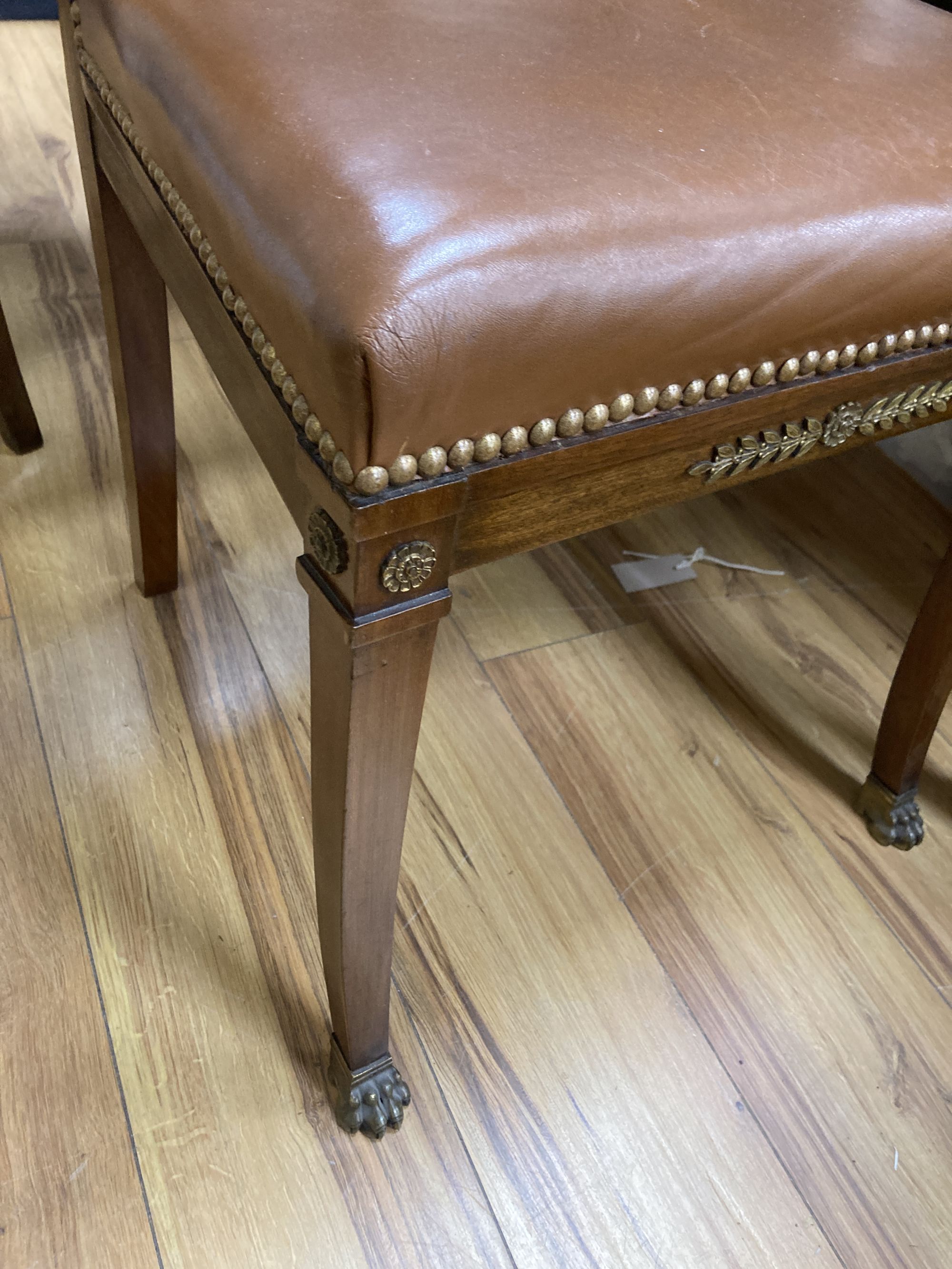 A set of six Empire style brass mounted mahogany dining chairs with tan leather upholstery